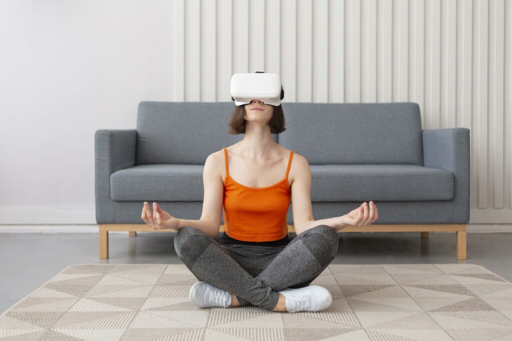 femme assise en tailleur dans une pièce avec un canapé en fond, portant un casque de réalité virtuelle sur la tête et étant en train de méditer